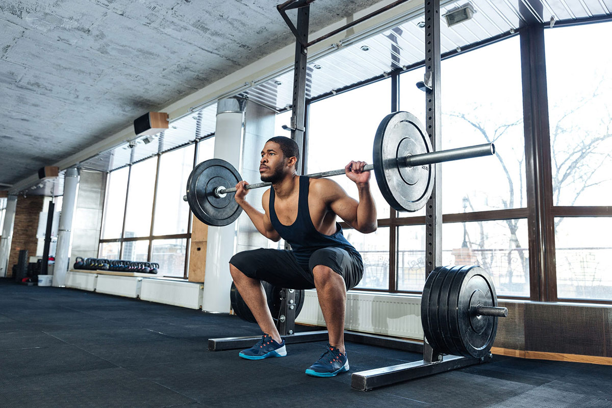Fit-Man-In-Squatting-Position-Using-Squat-Rack-And-Weights