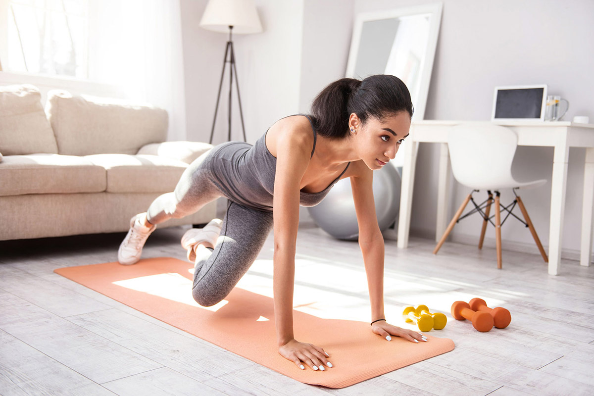 young woman doing planks while alternating legs in her living room