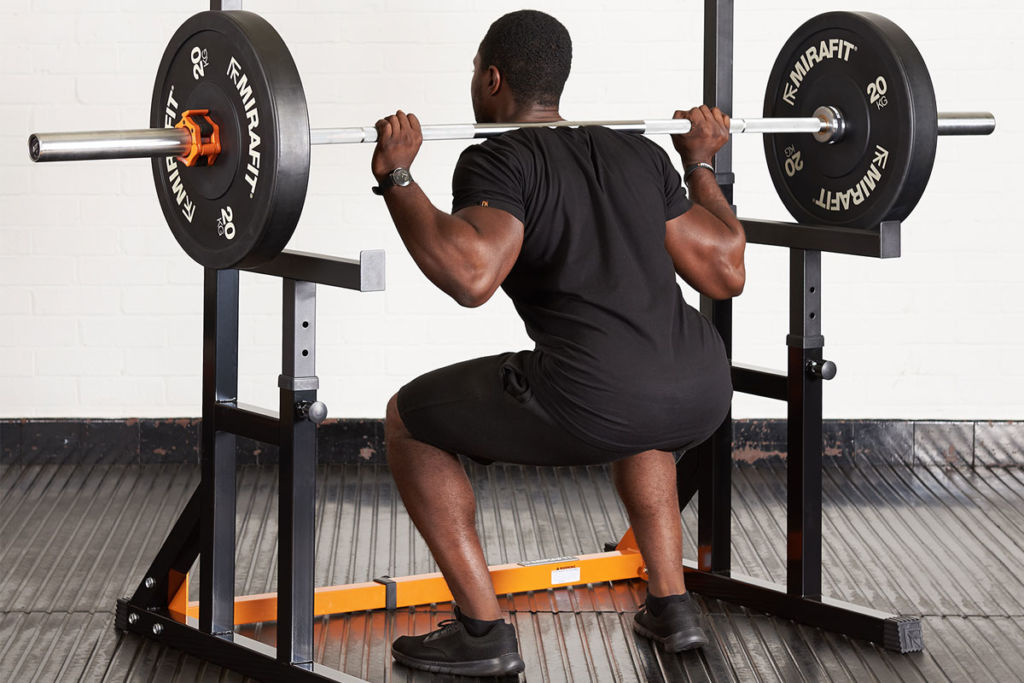 fitness expert using mirafit adjustable squat rack kit to squat