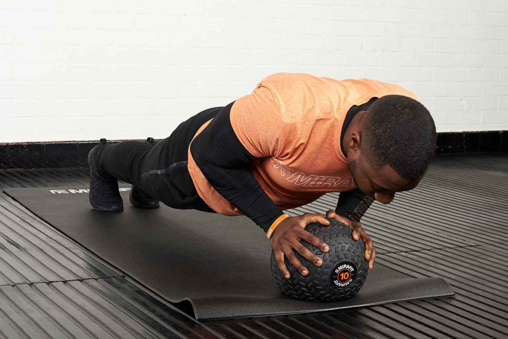 Man doing a push up holding a Mirafit tyre tread slam ball